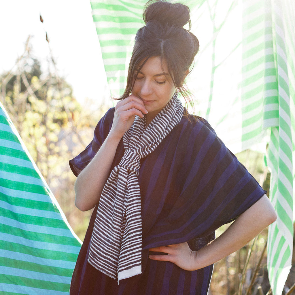 Woman surrounded by striped sarongs wearing a black and white striped neck scarf